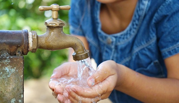 Bambino che utilizza un rubinetto esterno in una località tunisina, a rappresentazione delle disuguaglianze nell’accesso all’acqua in un contesto di stress idrico.