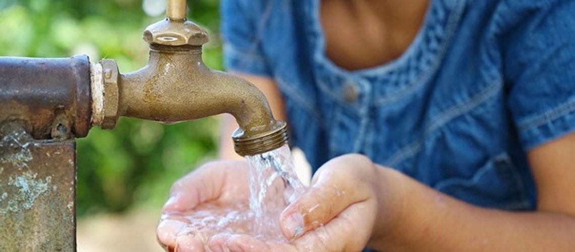 Bambino che utilizza un rubinetto esterno in una località tunisina, a rappresentazione delle disuguaglianze nell’accesso all’acqua in un contesto di stress idrico.