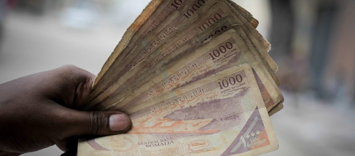 A man holds up Somali shilling notes having just exchanged US Dollars with a money changer on the streets of the Somali capital Mogadishu. Millions of people in the Horn of Africa nation Somalia rely on money sent from their relatives and friends abroad in the form of remittances in order to survive, but it is feared that a decision by Barclays Bank to close the accounts of some of the biggest Somali money transfer firms – due to be announced this week - will have a devastating effect on the country and its people. According to the United Nations Development Programme (UNDP), an estimated $1.6 billion US dollars is sent back annually by Somalis living in Europe and North America. Some money transfer companies in Somalia have been accused of being used by pirates to launder money received form ransoms as well as used by Al Qaeda-affiliated extremist group al Shabaab group to fund their terrorist activities and operations in Somalia and the wider East African region. AU/UN IST PHOTO / STUART PRICE. Original public domain image from Flickr